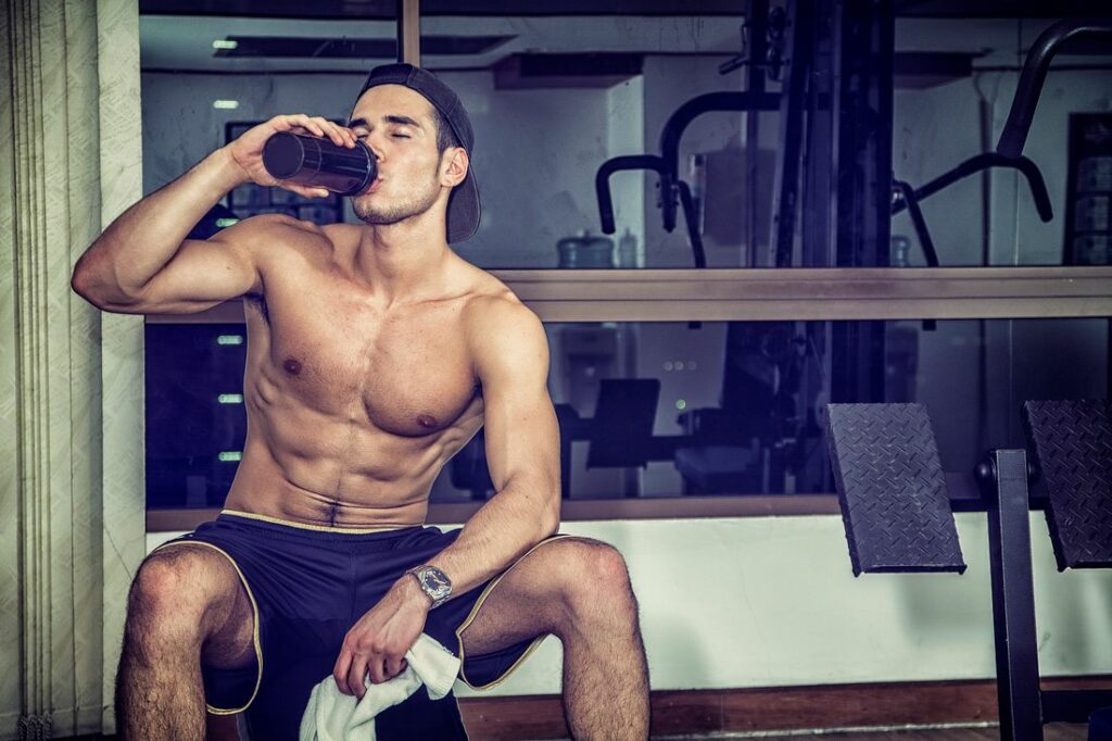 shirtless-young-man-drinking-protein-shake-in-gym