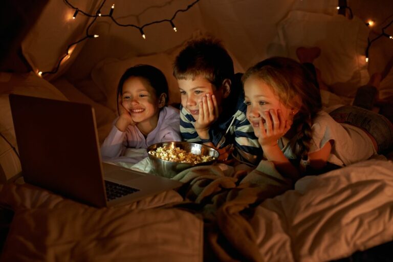 movie-time-in-the-pillow-fort-three-young-children-using-a-laptop-in-a-blanket-fort