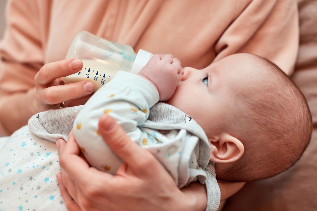 mother-feeds-little-cute-newborn-daughter-with-milk-bottle