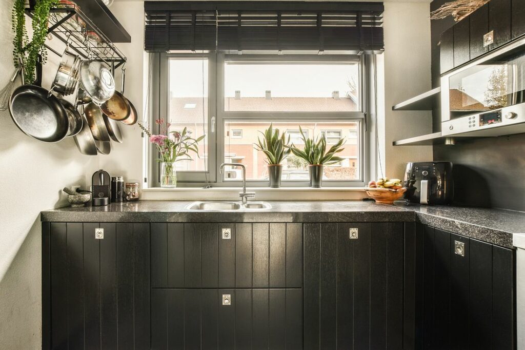 a-small-kitchen-with-black-cabinets-and-a-window