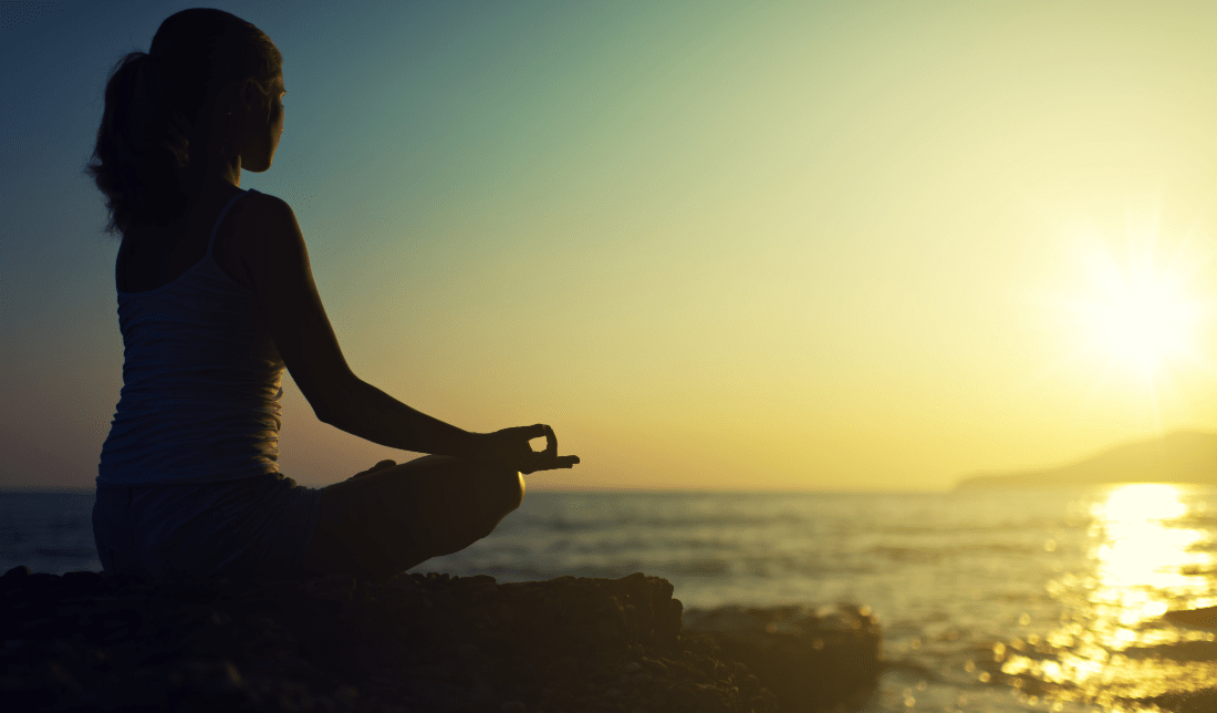 female silhouette in a lotus position surrounded by nature