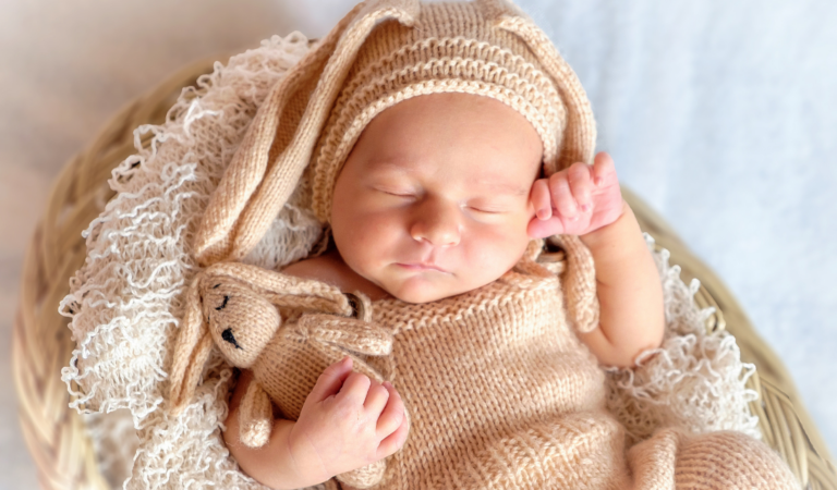newborn baby surrounded by baby products